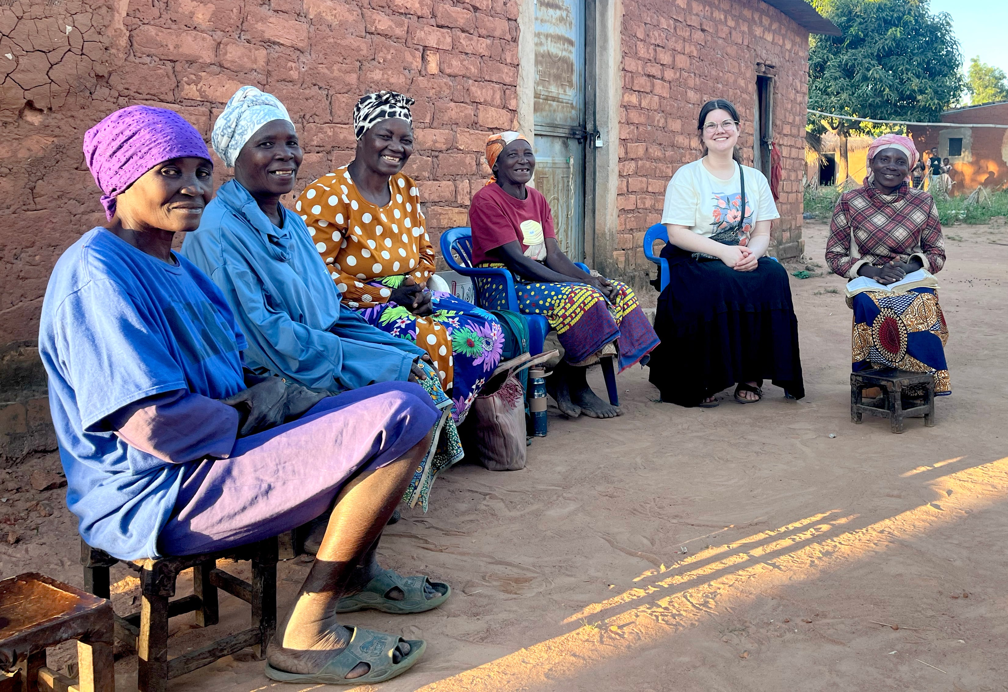 During an Immersion 15 assignment, a young adult participant spends time with local community members outside a village home, building relationships and learning from the people and culture through shared conversation.